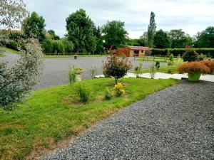 a gravel driveway with flowers in a yard at LE CLOS DES PRAIRIES Suite 2 grandes chambres in Saint-Yan