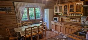 eine Küche mit einem Tisch und Stühlen sowie einem Kühlschrank in der Unterkunft Leśniczówka Przysietnica in Przysietnica