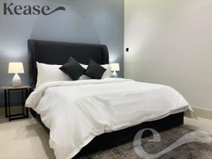 um quarto com uma cama com lençóis brancos e almofadas pretas em Kease Tawun A5-2 Royal touch Terrace XZ48 em Riyadh
