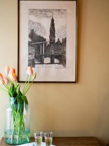 a picture hanging above a table with flowers in a vase at BnB 117 in Amsterdam