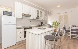 una cocina con armarios blancos y una isla de cocina con sillas en Iris Holiday home en Trbounje