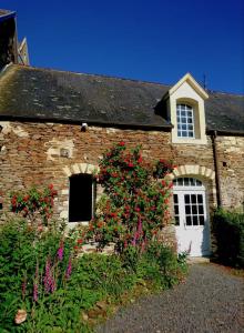a brick house with a white door and flowers at Chateau Normandie in Planquery