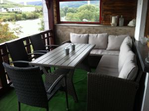 a table and chairs and a couch on a porch at 'Ferienhaus Mosel' mit kostenfreien ÖPNV-Ticket in Ürzig