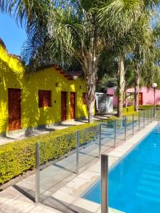 a pool in front of a yellow house with trees at Cabañas Puertas del Sol in La Rioja