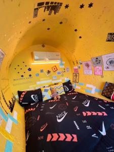 um quarto com uma cama numa parede amarela em 與大自然融合的包棟小屋 em Hengchun South Gate