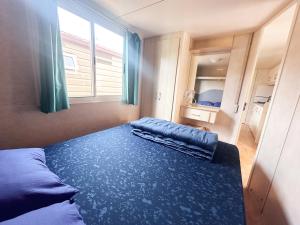 Schlafzimmer mit einem Bett mit blauer Bettwäsche und einem Fenster in der Unterkunft TuscanyChalets - luxe family chalet near sea with pool in Viareggio
