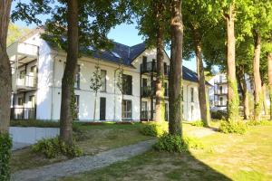 an exterior view of a white house with trees at Bernsteinquartier Ferienwohnung Blaues Fenster in Kölpinsee