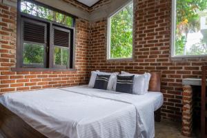 uma cama num quarto de tijolos com duas janelas em Dollyz Home - Sri Lanka em Ambalangoda