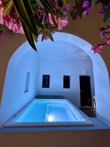a large swimming pool with a blue light in a room at Santorini Miracles Suites in Perissa