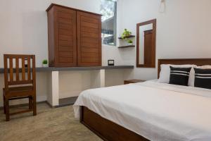 um quarto com uma cama, um armário de madeira e uma cadeira em Dollyz Home - Sri Lanka em Ambalangoda