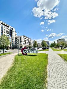 a cocacola sign sitting on the grass next to a sidewalk at Kasper Coresi Mall - Rise Private Apartments & Suites in Braşov