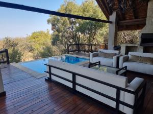 a patio with a pool and furniture on a wooden deck at Mingwe Private Game Lodge in Mabula