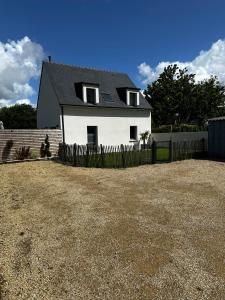 una casa blanca con techo negro y valla en Maison Ker Ria, en Locoal-Mendon