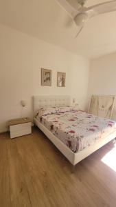 a white bedroom with a bed and a wooden floor at Elba in relax in Rio Marina +14 photos