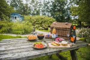 una mesa de picnic con comida y bebida y una jaula para aves en Tiny Houses Bij De Compagnons en Waskemeer