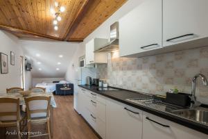 een keuken met witte kasten en een tafel en een eetkamer bij Arieli Apartments Izola in Izola