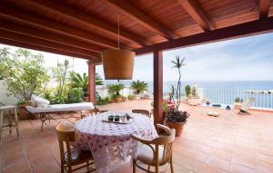 un patio con mesa, sillas y el océano en Villa Eugenia, en Favazzina