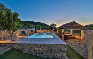 een zwembad in een tuin met een stenen muur bij Beautiful Home In Trolokve With Kitchen in Prgomet