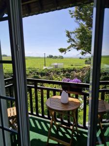 a table on a balcony with a view of a field at Chambre d'hôte proche d'Étretat in Saint-Jouin-Bruneval