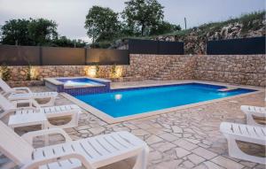 una piscina con sillas blancas y una pared de piedra en Cozy Home In Gornji Prolosac With Kitchen en Gornji Proložac