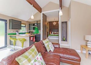 a living room with a brown leather couch and a kitchen at Oakwood Lodges in Skipwith