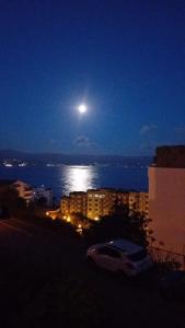 a full moon over the water at night at AJACCIO VUE MER ET MONTAGNES JACUZZI 300M PLAGEs in Ajaccio +1 photo