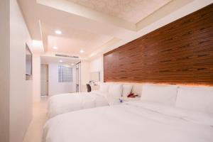duas camas num quarto de hotel com lençóis brancos em Duke Business Hotel em Zhongli