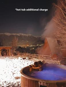 a woman laying in a hot tub in the snow at Bran Mountain Living in Bran