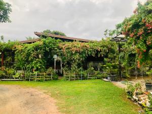 een huis bedekt met planten en een tuin bij Baan Thung Home Stay in Prasat