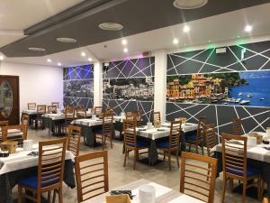 Hotel Portofino في كاورلي: مطعم بطاولات وكراسي وجدار كبير جداري