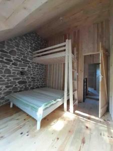 a bunk bed in a room with a stone wall at La Grange de la Gratade in Rochefort-Montagne