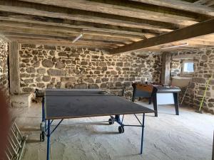 a ping pong table in a room with a brick wall at La Grange de la Gratade in Rochefort-Montagne