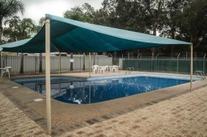 a blue canopy over a pool with tables and chairs at Acclaim Swan Valley Tourist Park in West Swan