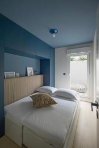 a bedroom with a large white bed with a blue wall at Design Coastal Garden Apartment in Split