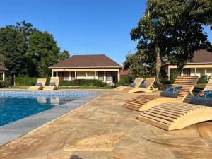 una piscina con tumbonas junto a una casa en Tanzania Safari Lodge en Arusha