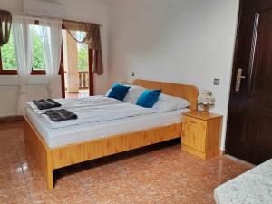 ein Schlafzimmer mit einem großen Holzbett mit blauen Kissen in der Unterkunft NORA Guesthouse and Restaurant in Zamárdi