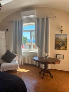 a living room with a table and a window at Villa Sea view con terrazza e giardino in Capri