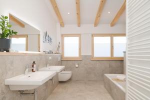 a bathroom with two sinks and a toilet and a tub at FENJOY Ferienapartments am Chiemsee mit Bergblick in Bernau am Chiemsee +47 photos