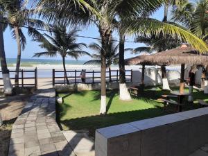 un resort con tavoli, palme e spiaggia di Pousada Robijn a Cabo de Santo Agostinho