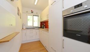 a kitchen with white cabinets and a microwave oven at Cozy House above Lake Lucerne in car-free Vitznau Mittlerschwanden at Mount Rigi railway in Vitznau