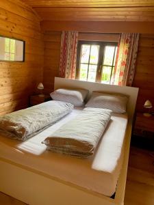 ein Bett in einem Blockhaus mit zwei Kissen darauf in der Unterkunft Ferienhaus Thelen in Niederhersdorf