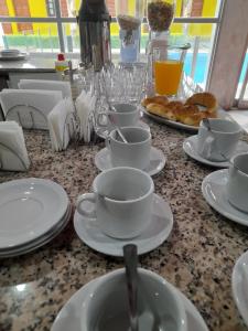 a table with white cups and saucers and pastries on it at Cabañas Puertas del Sol in La Rioja