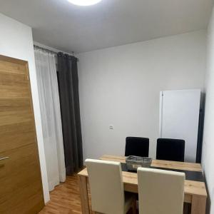 mesa de comedor con sillas y pared blanca en Dado apartman 2 en Kraljevo