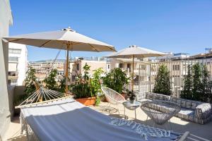 eine Terrasse mit Tischen, Stühlen und Sonnenschirmen in der Unterkunft Yalarent Stunning Apartments at the Heart of Athens in Athen