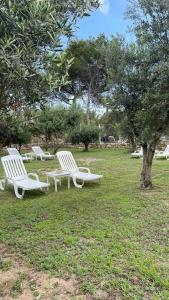 three white chairs sitting in the grass in a park at Calafato Guest House in Favignana