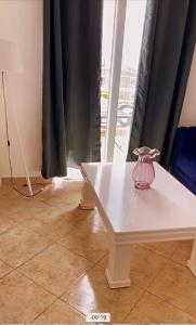 Apartments Harmony في أولتسينج: وجود مزهرية وردية على طاولة بيضاء في غرفة
