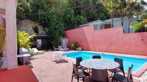 un patio con tavolo e sedie accanto alla piscina di Les gîtes de Bunel a Les Abymes