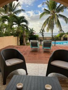 a patio with two chairs and a table and palm trees at Apartment with exceptional sea view in Trou aux Biches