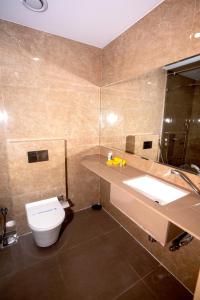 uma casa de banho com um WC, um lavatório e um espelho. em Nulife Resort em Jamnagar