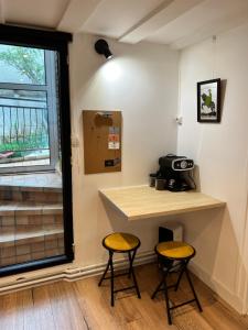 a small table and two stools in a room with a window at La maison des artistes in Savigny-sur-Orge +7 photos